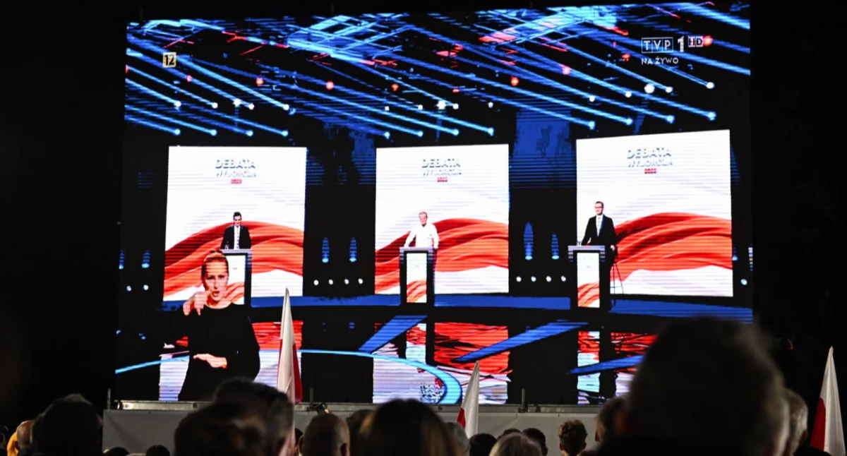Debata w TVP głównie między M. Morawieckim i D. Tuskiem; w tle wazon od Putina i zaproszenie na debatę dla prezesa PiS