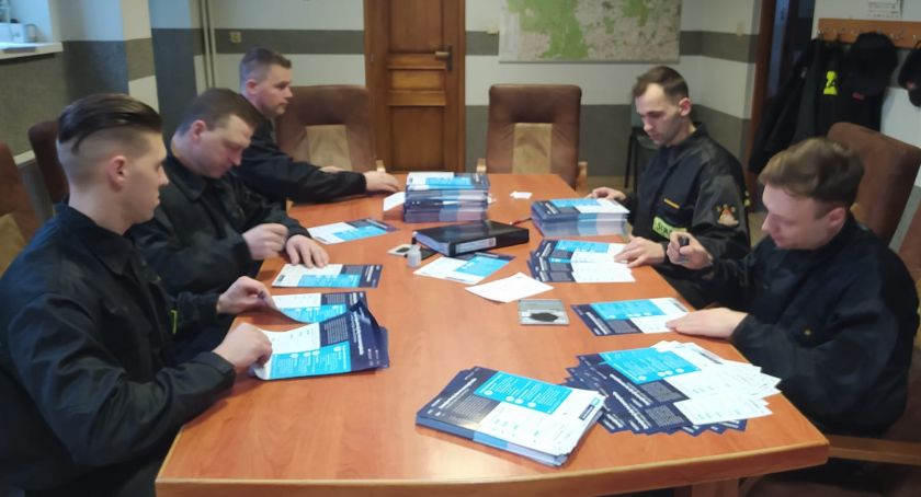 Zlotowscy strażacy przygotowują ulotki zachęcajace do szczepienia przeciw COVID19