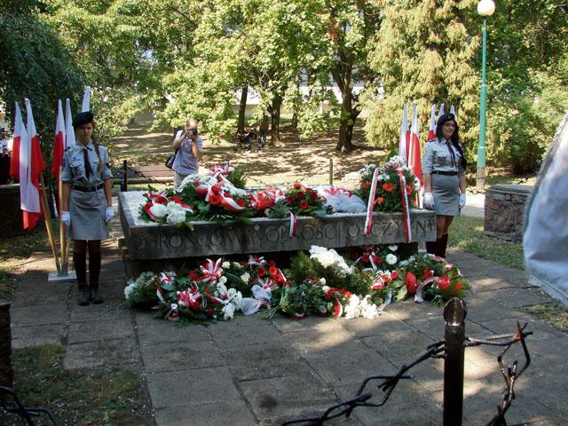 Sztandary i kwiaty przy pomniku poległych