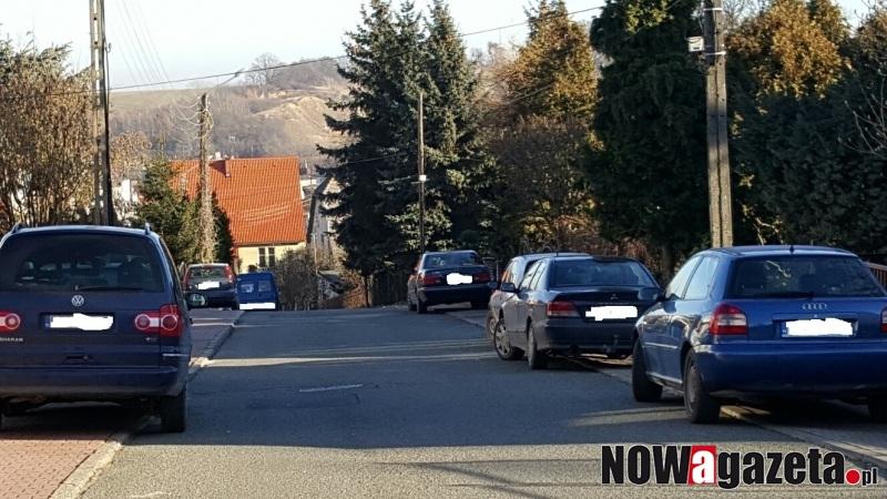 Samochody stoją na chodniku, piesi idą jezdnią