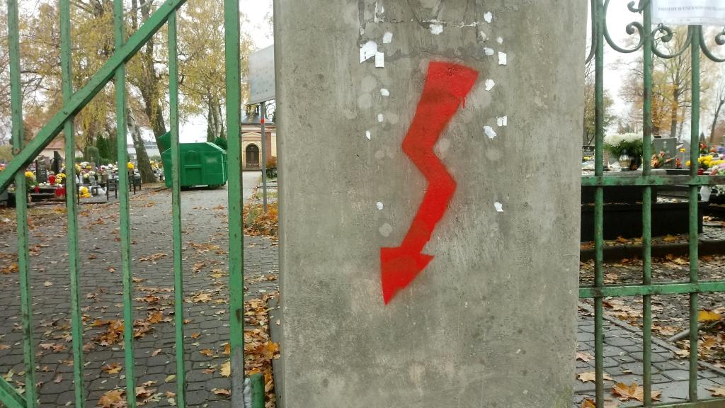 Czerwone błyskawice na murze cmentarza