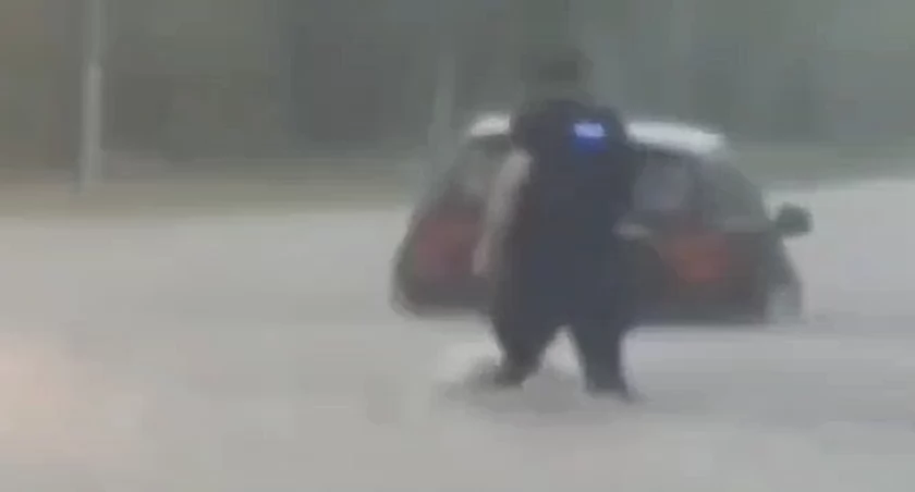  Policjanci interweniujący na zalanej ulicy pomogli kobiecie wydostać się z auta