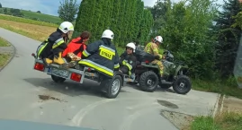 Zdjęcie przedstawia: Do chorego w Brzezinach dotarli Vitarą strażaka. Do karetki wieźli na przyczepce zapiętej do quada