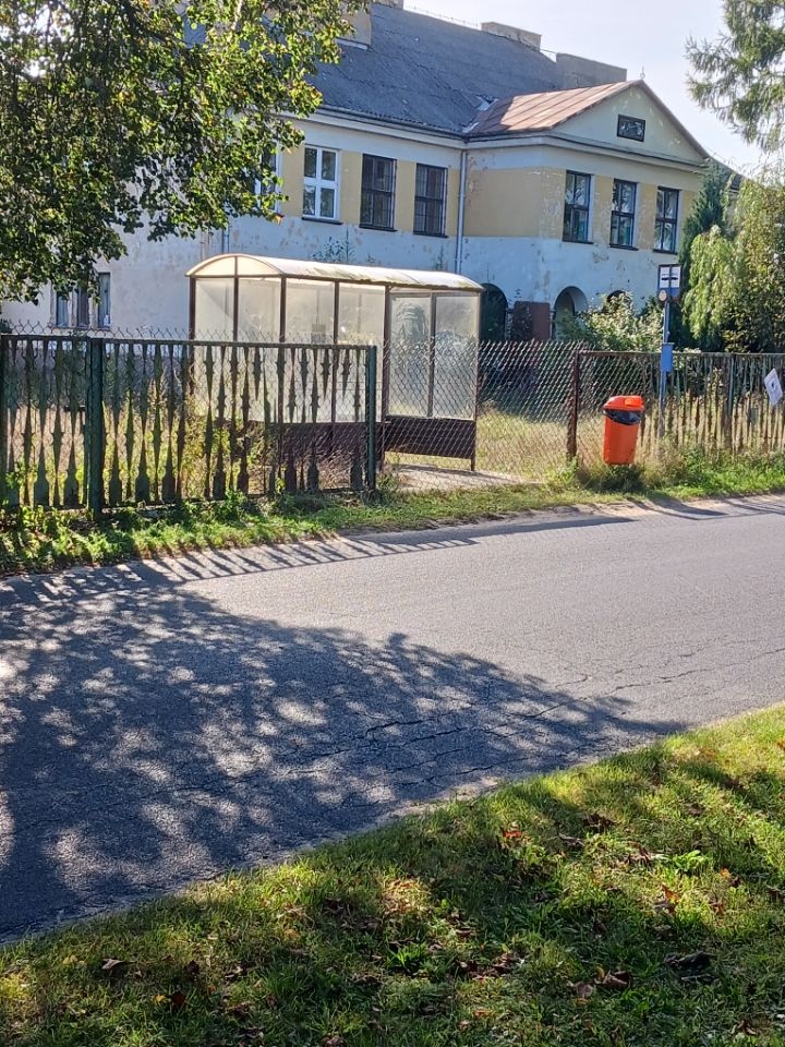 Cały przystanek z wiatą został zagrodzony wysoką siatką. Dzieci stoją na skraju jezdni!