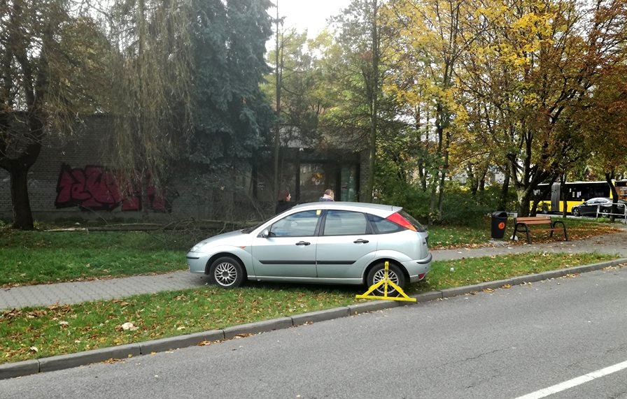 Samochód z blokadą stoi na trawniku i blokuje chodnik