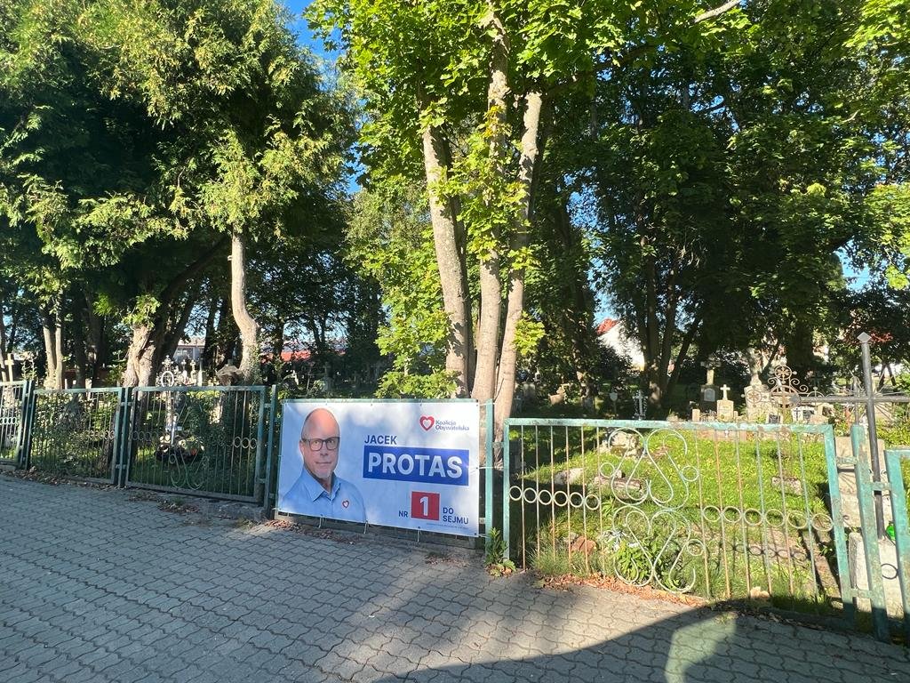 Jacek Protas wisi na ogrodzeniu cmentarza w Pieniężnie. Czy to nekropolityka?