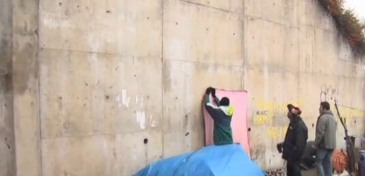 Banksy za czerwoną płachtą zdobi mur w Calais