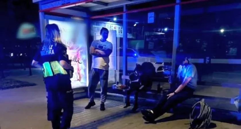 Pijany ojciec z kolegą na przystanku. Obok nich pięciolatka przysypiała na ławce