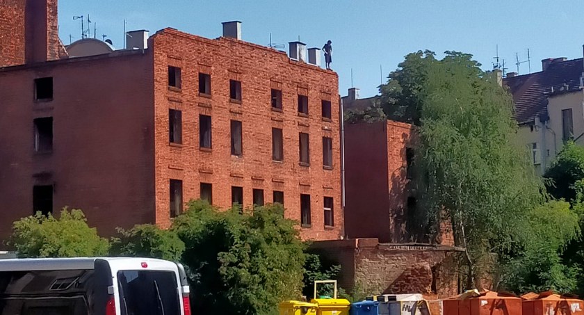 Młody człowiek stoi na dachu dawnego hotelu w Legnicy. Mężczyzna grozi, że popełni samobójstwo